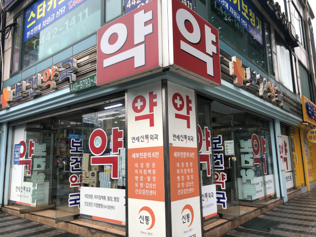 Außenansicht einer modernen Glaswand-Apotheke in Seoul, Südkorea, mit Text, der angibt, dass es die erste Apotheke der Stadt ist.