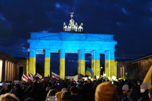 Eine Menschenmenge steht vor dem Reichstagsgebäude in Berlin, Deutschland, mit Fahnen und Plakaten, mit einer Fahne auf der rechten Seite.