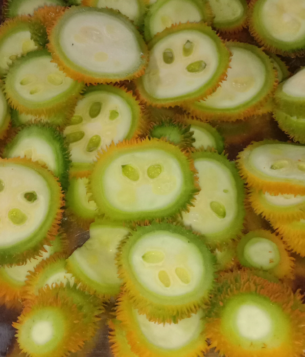 Nahaufnahme einer runden, stacheligen Durian-Frucht mit gelbgrüner Außenseite und weißem Inneren, die auf einem Tisch liegt.