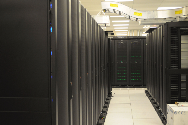 Ein Rechenzentrum mit einer Reihe von Servern, beleuchtet von Deckenlampen, ordentlich und gut beleuchtet.