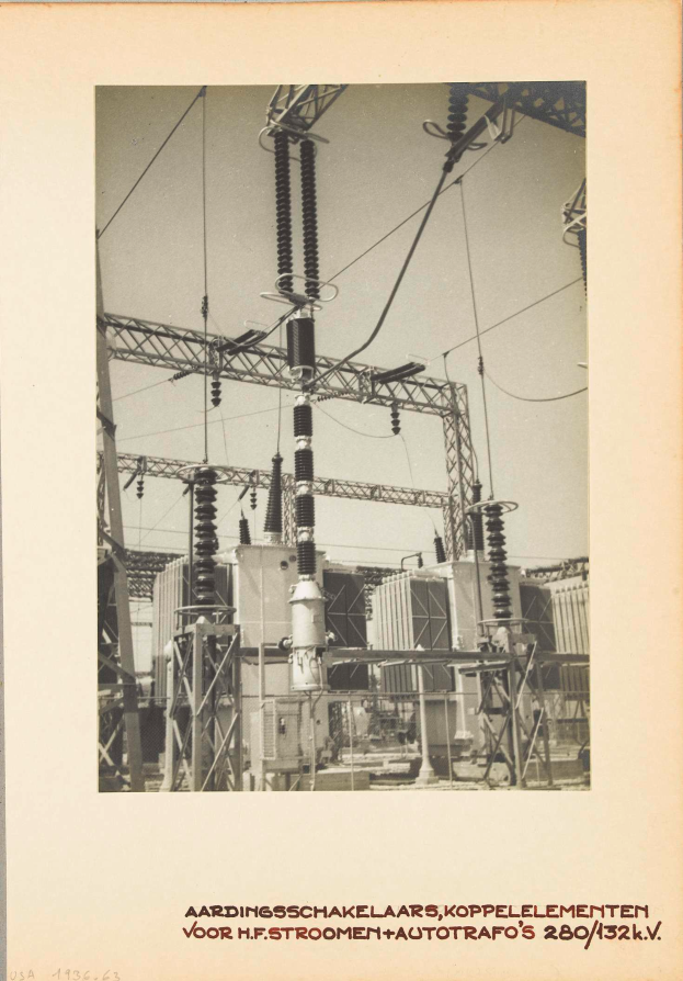 Ein altes Schwarz-Weiß-Foto einer elektrischen Umspannstation mit sichtbaren Transformatoren, Drähten und Text am unteren Rand.