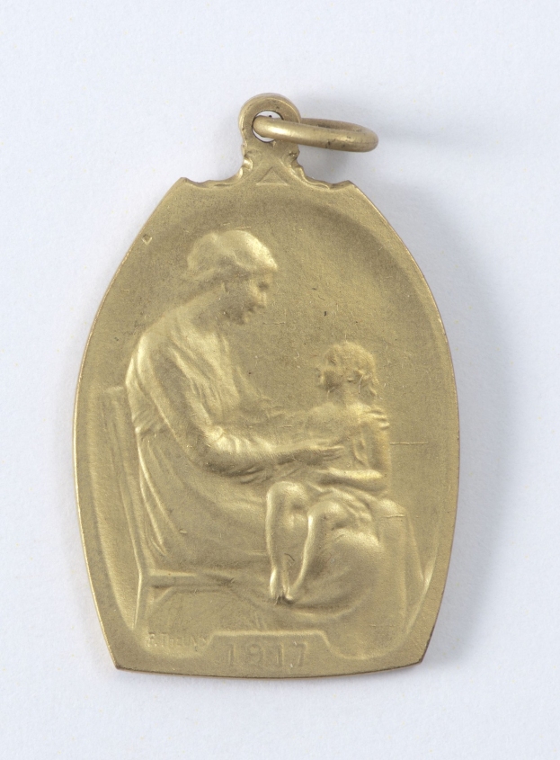 Goldmedaille mit einer Reliefdarstellung einer Frau in einem weißen Kleid mit einem Knoten im Haar, die ein Kind hält, beide schauen sich zärtlich an, beschriftet mit "Mutter und Kind."