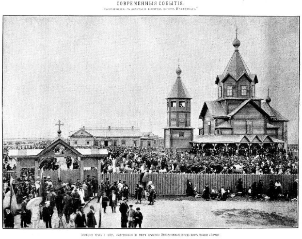 Schwarzes und weißes Foto einer Menge vor der Kirche der Interzession an der Nerl mit einem hölzernen Zaun im Vordergrund und Gebäuden im Hintergrund.