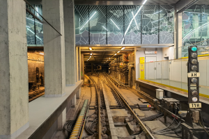 Ein Bahnhof mit einem Zug auf den Gleisen, beleuchtet von Oberlichtern, mit einer Plattform und Säulen auf der linken Seite und einem Signal mit einem Mast auf der rechten Seite, Teil der kürzlich wiedereröffneten London Underground.