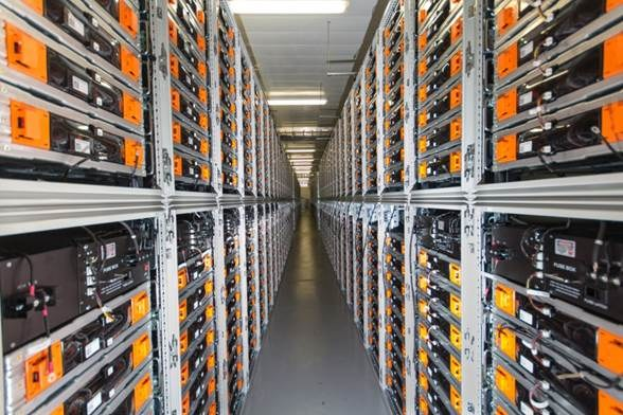 Eine lange Reihe von Servern in einem Rechenzentrum mit elektronischen Geräten in den Räckern und Anzeigelichtern oben.