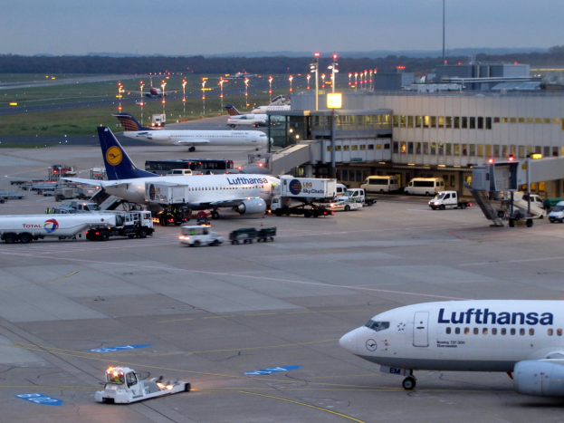 Lufthansa Airbus A330-300 Flugzeug am Frankfurt Airport geparkt mit Flughafeninfrastruktur, Fahrzeugen und Grünfläche im Vordergrund unter einem klaren blauen Himmel.
