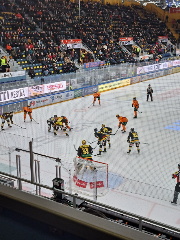 Gruppe von Menschen, die Hockey auf einem Eisstadion mit Zuschauern, Bannern und Flutlicht spielen