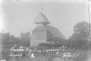 Ein altes Schwarz-Weiß-Foto der Kirche des Heiligen Grabes, umgeben von Bäumen und Pflanzen, mit einem bewölkten Himmel im Hintergrund.