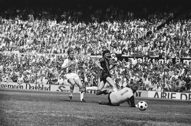 Schwarzes Foto von Männern, die auf einem Feld Fußball spielen, mit Zuschauern im Hintergrund und einer Tafel mit der Aufschrift "Bundesliga 1978-79 Ajax 1-1 Hannover 96."