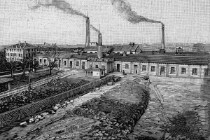 Eine Schwarz-Weiß-Zeichnung einer Fabrik mit Rauch, der aus ihren Schornsteinen aufsteigt, umgeben von Gebäuden, Bäumen, Pflanzen, Pfählen und Bahnschienen, mit dem Text "1892 - die Fabrik des Eisenoxids" unten.