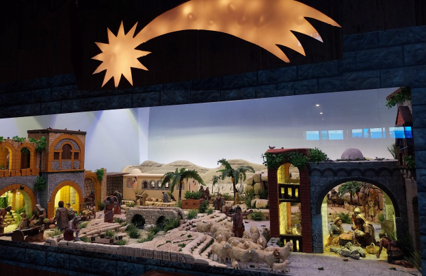 Krippenausstellung im Museum mit Figuren, Tieren, Häusern, Bäumen und Pflanzen, beleuchtet von einem Spotlight.