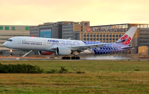 Ein Airbus A350-900 der China Airlines startet vom Beijing Capital International Airport, umgeben von grünem Gras und Pflanzen, mit Gebäuden im Hintergrund und einem klaren blauen Himmel.
