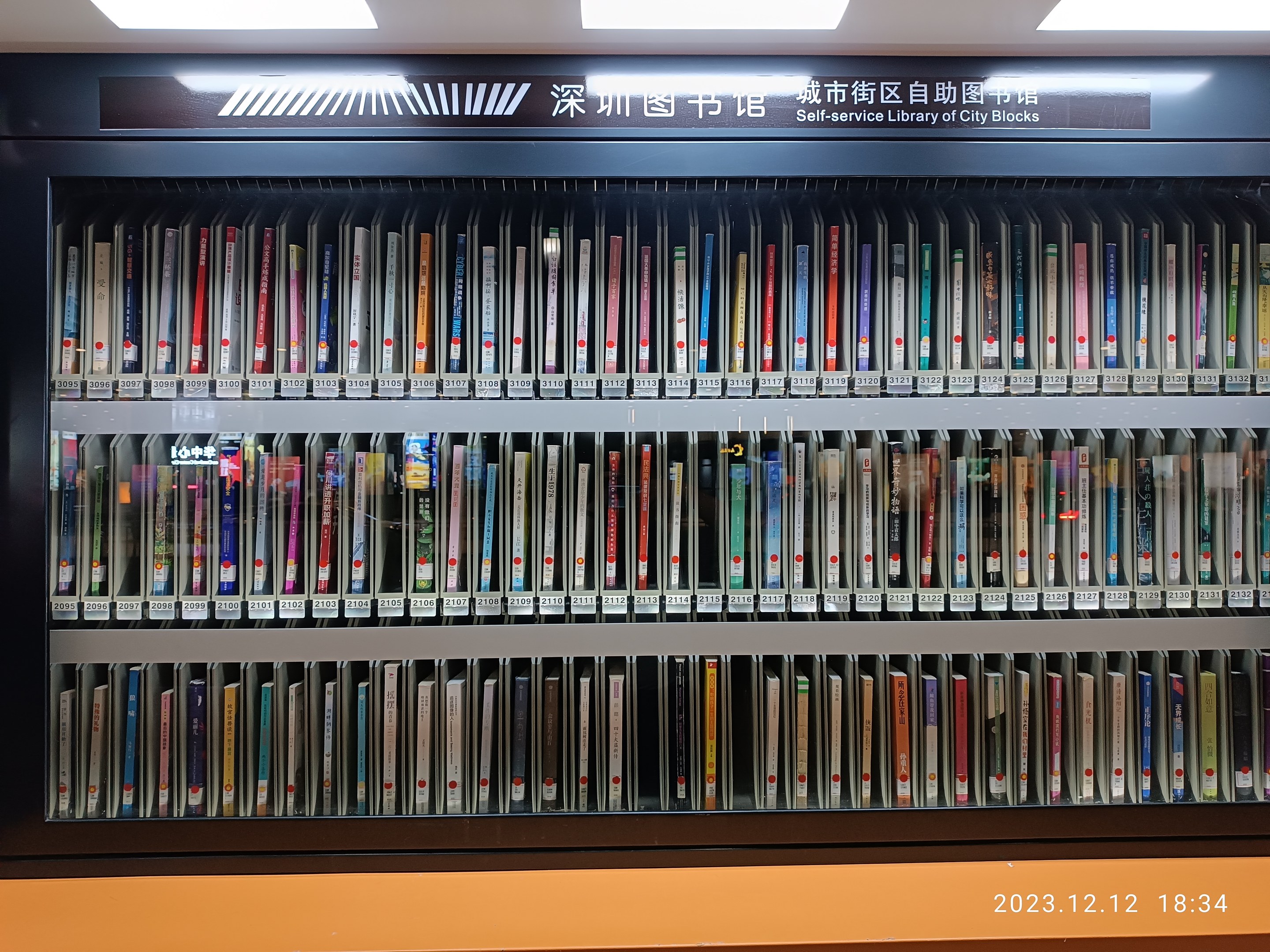 Eine gut beleuchtete Bibliothek mit Reihen von Bücherregalen, einer Texttafel und einem Wasserzeichen unten.