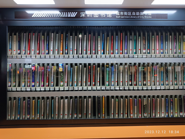 Eine gut beleuchtete Bibliothek mit Reihen von Bücherregalen, einer Texttafel und einem Wasserzeichen unten.