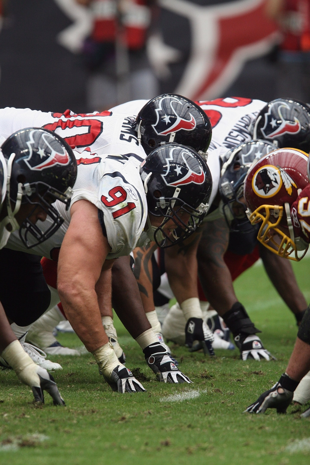 Eine Gruppe von Fußballspielern in Helmen und Handschuhen steht auf dem Feld mit einem unscharfen Hintergrund.