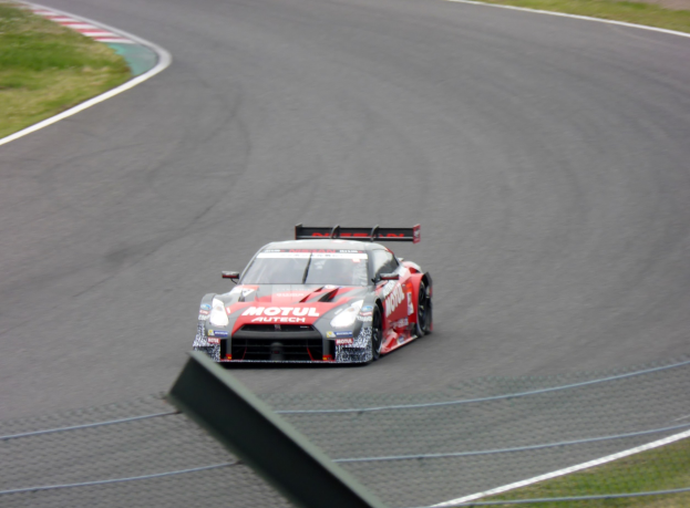 Nissan GT-R Nismo GT3 Rennauto auf der Nürburgring 24 Stunden Strecke, umgeben von grünem Gras auf beiden Seiten.