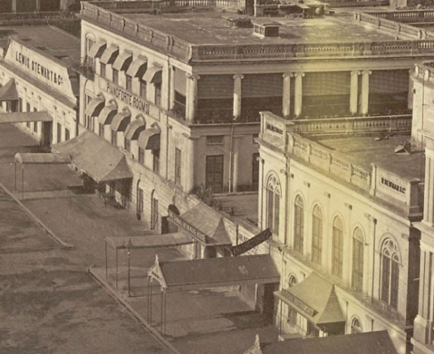 Schwarzes und wei├čes Foto einer Stra├če mit Geb├Ąuden, Fenstern, S├Ąulen, Namensschildern, Hütten und Masten.