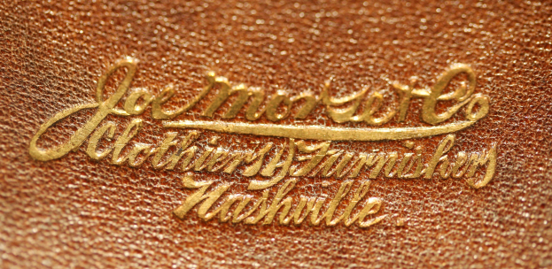 Nahaufnahme einer braunen Lederhandtasche mit goldener Schrift, die einen luxuriösen und eleganten Eindruck vermittelt.