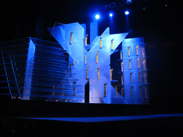 Bühne für eine Preisverleihung mit dunklem Hintergrund und minimaler Beleuchtung, die ein paar Gegenstände auf der Bühne zeigt.