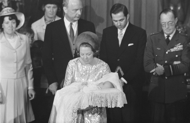 Königin Elizabeth II wiegt ihren neugeborenen Sohn, Prinz Philip, während Prinz Philip, Herzog von Edinburgh, neben ihnen in einem Anzug und Krawatte steht, mit Vorhängen im Hintergrund.