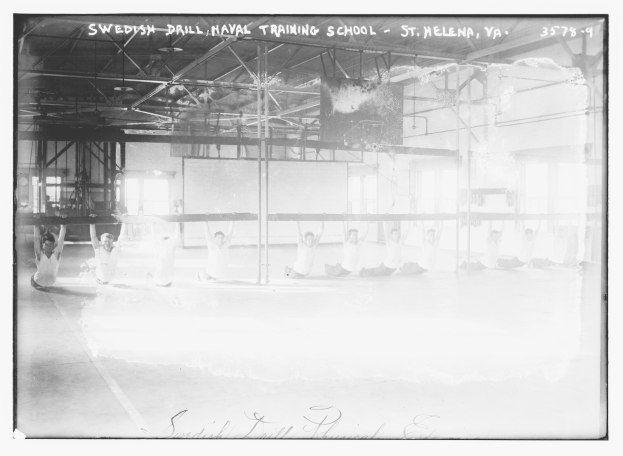 Black and white photo of a group performing gymnastics in a gym with poles, rods, windows, and a wall in the background, featuring text at the top and bottom.